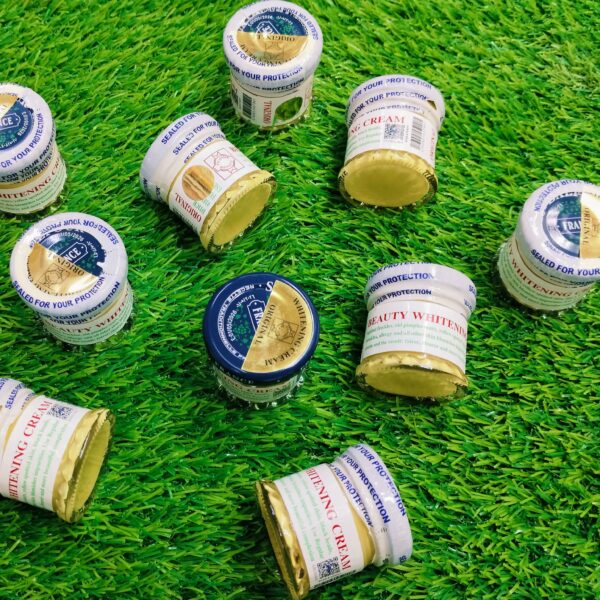 Multiple jars of cream with visible labels on a green grass background