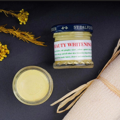 Beauty whitening cream jar with open lid on a dark surface with decorative elements.