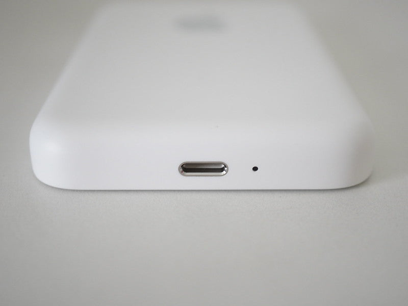Close-up of a white electronic device with a USB-C port on a light gray background